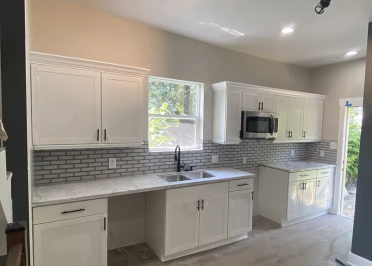 Kitchen with white shaker cabinets, granite counters and a gray tile backsplash