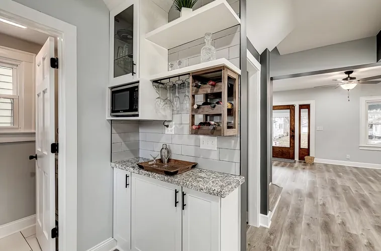 Kitchen nook with white cabinets, a microwave shelf and wood look flooring