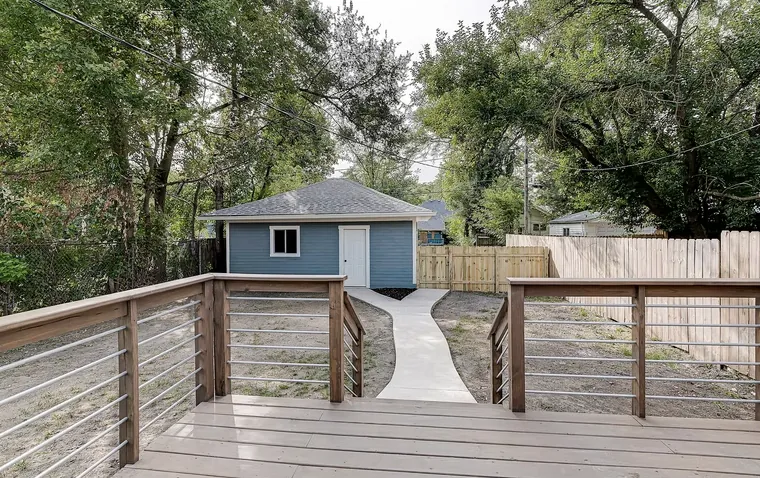 Deck and concrete walkway leading to a small blue outbuilding