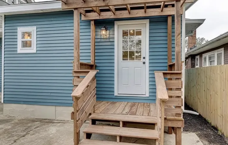 Blue sided building with new wooden porch steps and a pergola