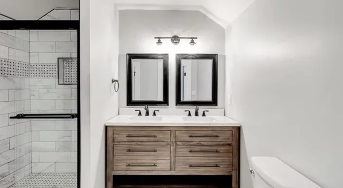Bathroom double vanity with two black framed mirrors and a tiled shower