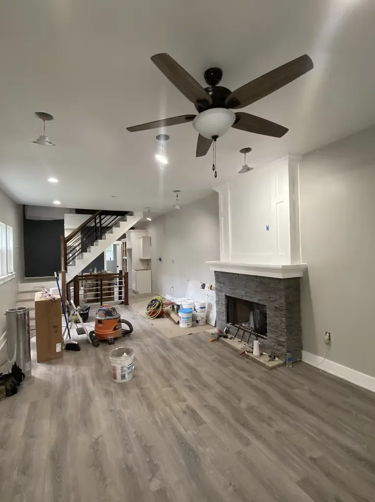 Living room with a ceiling fan, stone fireplace and new plank flooring