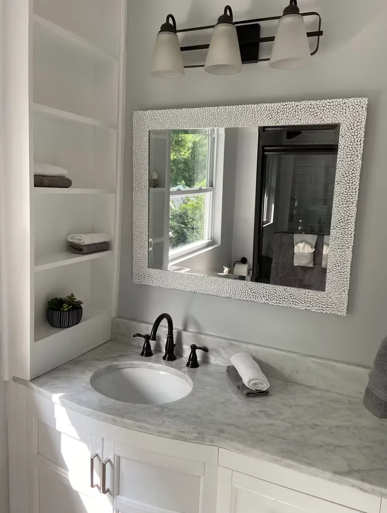 Bathroom vanity with a framed mirror, built-in shelves and a white sink